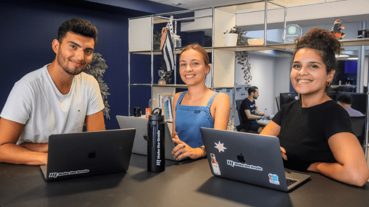 Paul, Marion et Ghislaine travaillent sur une table haute et sourient